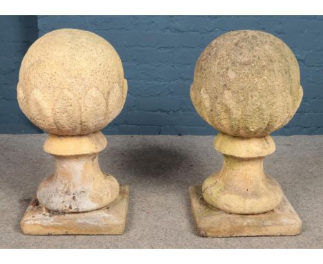 A pair of garden spheres in jagged surround, mounted on baluster columns raised on square plinths. Height: 70cm, Width of pli