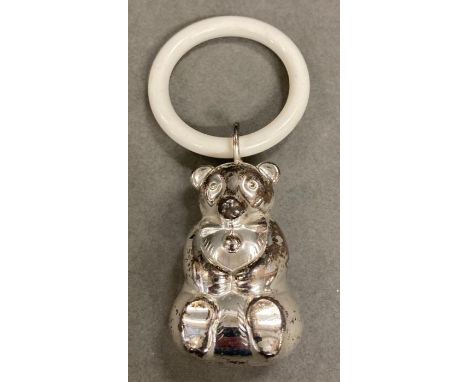 Vintage white metal baby rattle and teething ring in the form of a bear.