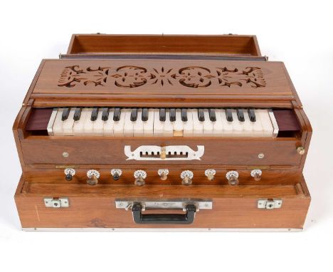 An Indian Samvadini (harmonium or pump organ), with 22 white keys and ten stops, in polished teak case, and outer carrying ca