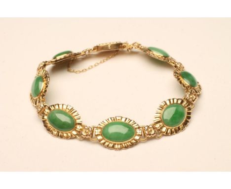 A JADE BRACELET, the seven cabochon polished oval panels in 14kt gold flowerhead mounts, with safety chain (Est. plus 18% pre