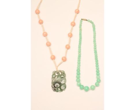 AN ART DECO JADEITE PENDANT of oblong form, the fascia carved and pierced with a bird perched upon a fruiting bough, the reve