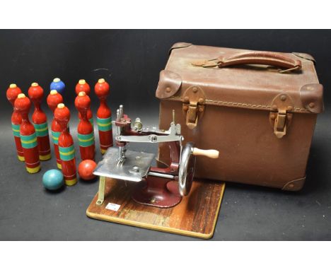 A child's manual sewing machine cased; a set of skittles.