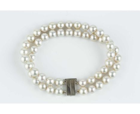 A cultured pearl double strand bracelet with platinum clasp, comprising two strands of uniform cultured pearls of silver-whit