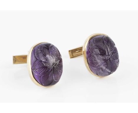 A pair of amethyst cufflinks, each oval amethyst cabochon with floral carved decoration, in collet settings, on hinged baton 