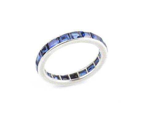 A sapphire full hoop ring by Cartier, channel set throughout with rectangular step-cut sapphires, white precious metal mounte