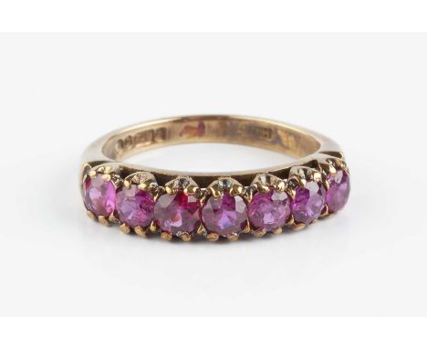 A ruby half hoop ring, designed as a line of seven circular mixed-cut rubies in claw settings, 9ct gold mounted, ring size ap