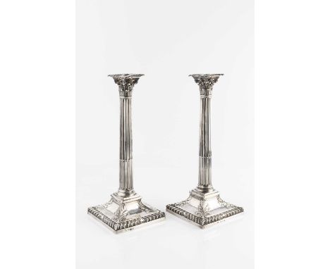 A pair of George III silver candlesticks, with fluted columns, Corinthian capitals and gadrooned square bases with foliate an