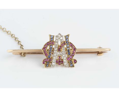 A ruby, sapphire and diamond set monogram bar brooch, the knife-edge bar centred with a pierced and millegrained monogram wit