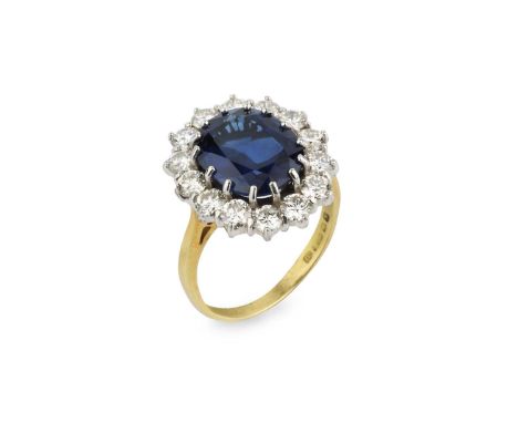 A sapphire and diamond cluster ring, the oval mixed-cut sapphire claw set within a border of round brilliant-cut diamonds, 18