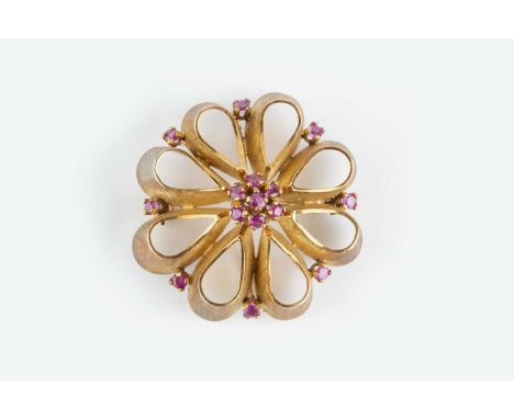 A ruby set panel brooch/pendant, modelled as an openwork stylised flowerhead of textured finish, centred with a cluster of ci