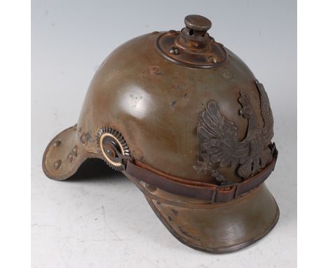 A Prussian Artillery? steel helmet, olive painted with pressed brass eagle plate, national cockades and three tame lobster ta