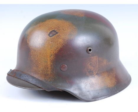 A German M1935 pattern steel helmet in camouflage finish, having a leather liner and chin strap, stamped to the interior ET58