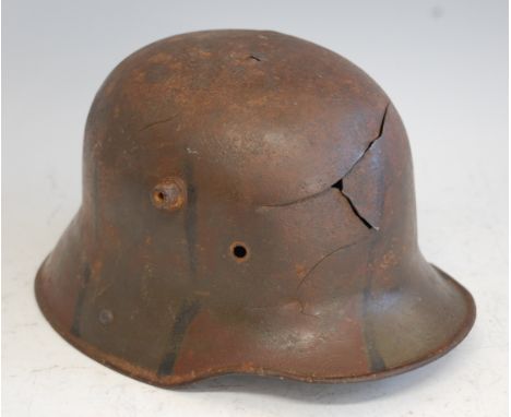 A German model M16 Stalhelm helmet with remains of camouflage finish and splits to front, lacking leather liner.