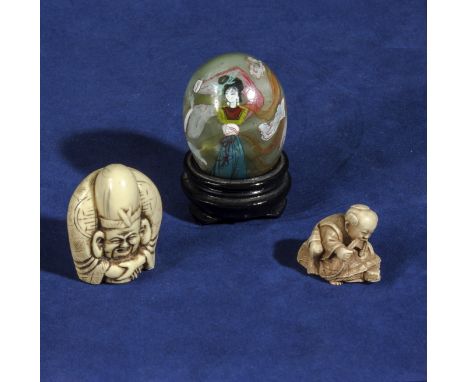 Two ivory netsuke together with a decorated piece of jade on a stand