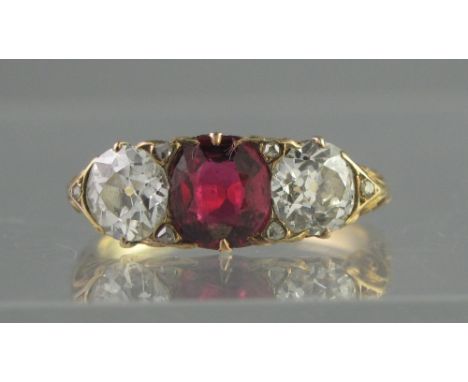 A VICTORIAN DIAMOND AND RUBY THREE STONE RING.  The central cushion cut ruby having an old cut diamond to either side, estima