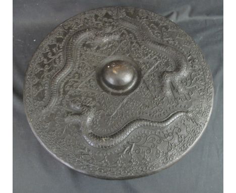 A CHINESE TARGE SHAPED BRONZE GONG overall relief decorated with scaly dragons and foliate scrolls. 46cm diameter. Together w