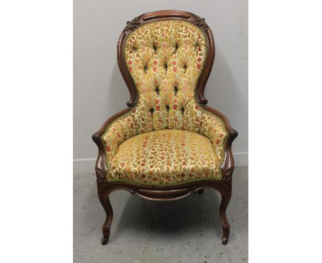 VICTORIAN WALNUT SHOW FRAME, SPOON BACKED FIRESIDE GENTLEMAN'S CHAIR, having buttoned upholstery with leaf and berry moulding