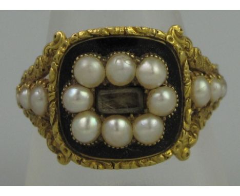 A GEORGIAN BLACK ENAMEL AND PEARL MOURNING RING.  The cushion shaped ring having central hair locket surrounded by eight pear