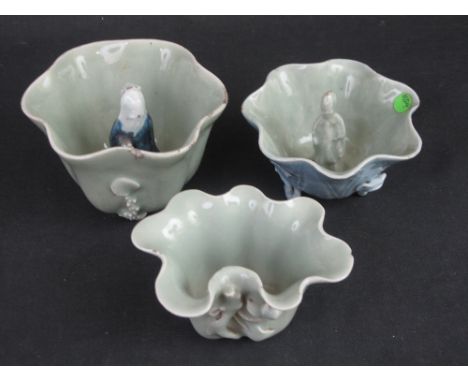 THREE CHINESE PORCELAIN CELADON GLAZED LOTUS LEAF FORM BRUSH WASHERS two of which have figural centres and one externally wit