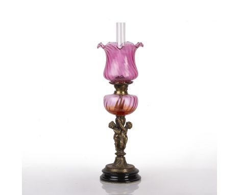 Oil lamp with cranberry glass shade and reservoir on brass stem, on circular base, 70cm high overall Condition: surface dust,