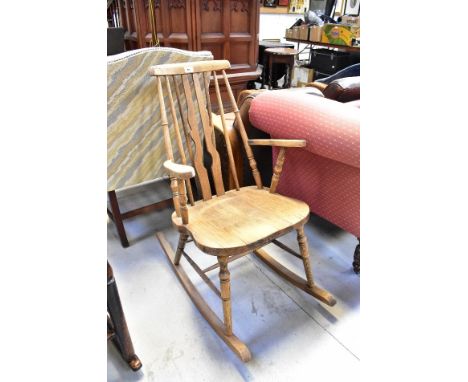 A late 19th/early 20th century stick back rocking chair with shaped arms, turned supports and H-stretcher, on rockers.