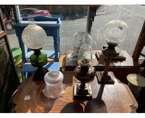 Three early to mid 20th century oil lamps to include an example with cast metal base and green glass reservoir, height 59cm, 