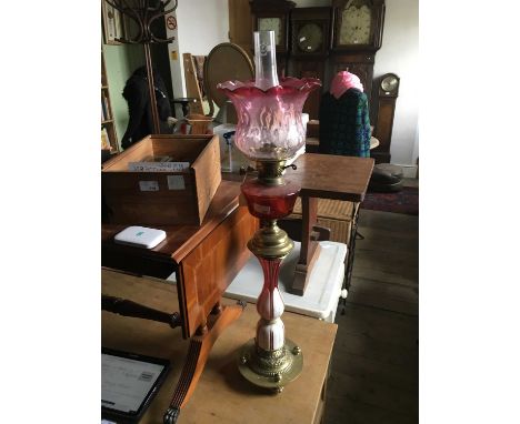 A Victorian Bohemian oil lamp with cranberry and clear glass moulded shade above a cranberry glass reservoir, brass column, a