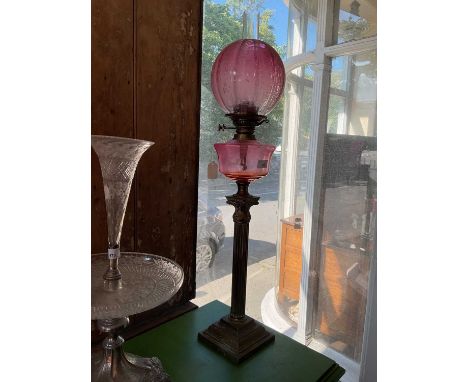 A Victorian oil lamp with cranberry and clear glass ball shade with etched floral decoration with a cranberry stepped glass r