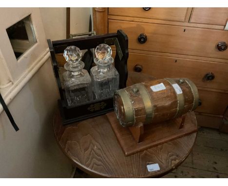 A modern tantalus housing two cut glass decanters, together with a brass bound oak spirit barrel on stand.