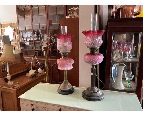Two Victorian oil lamps with cranberry and clear glass shades and cranberry milk glass reservoirs, height of largest (includi