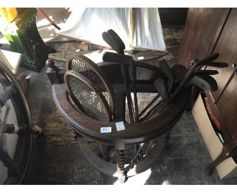 An early 20th century oak demi-lune stick stand containing an assortment of glof clubs and two tennis racquets.