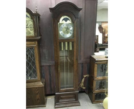 A modern oak longcase clock with arch top, rotating dial and visible pendulum, approx height 201cm.