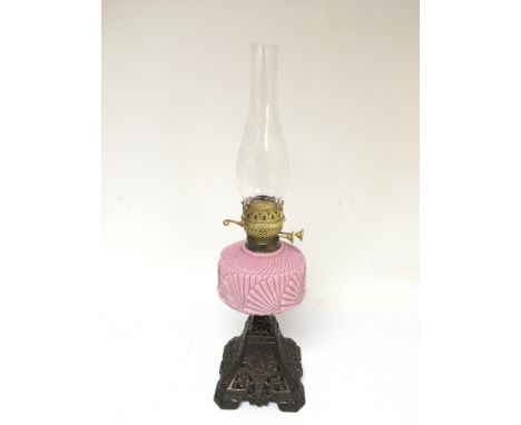 A brass oil lamp with a pink glass reservoir, approx height 59cm.