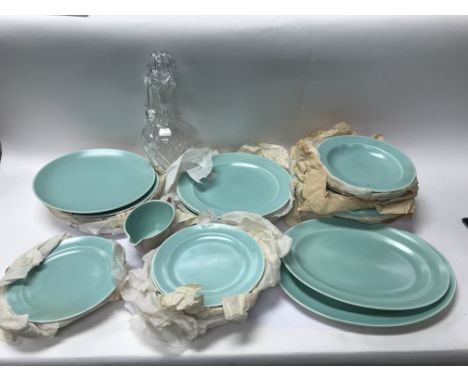 A group of Poole dinner service items including a gravy bowl, dinner plates and others alongside a glass decanter.