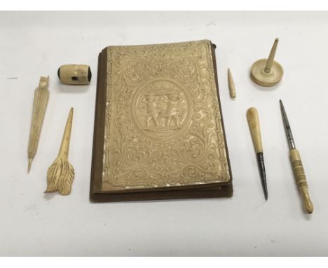 A collection of bone and ivory items plus a vintage notebook and pencil.