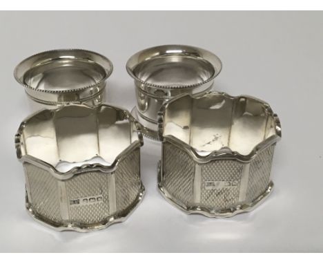 Two silver napkin rings with engine turned decoration and shaped edges and two other silver plated napkin rings.