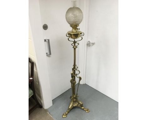 A freestanding brass oil lamp with a clear glass shade, approx height 157cm.