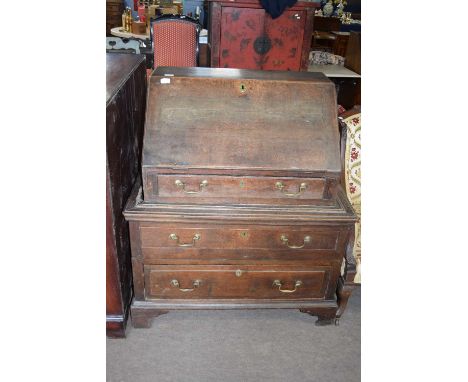 A composite oak fall front bureau with single drawer and fitted interior raised on a two-drawer oak chest base with bracket f