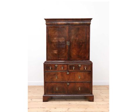 A walnut and feather-banded cabinet on chest, 18th century and later, the upper section with a cushion-moulded frieze drawer 