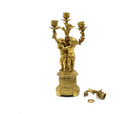 A gilt metal four light candelabra, the central sconce encompassed by three putti with outstretched arms, each holding furthe