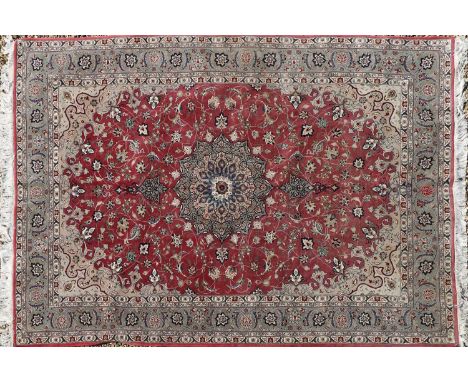 A wool and silk Tabriz carpet, with a central medallion to a red field, 303 x 202cmCondition report: Minor wear. Overall good