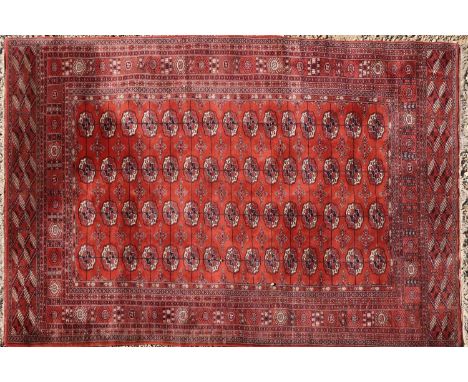 A Bokhara carpet, decorated with gul motifs to a red field, 304 x 202cmCondition report: Some losses to tassels. General wear