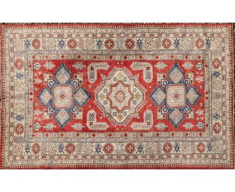 A Kazak carpet, centred with three medallions to a red field, 275 x 175cmCondition report: Losses to tassels, overall good or