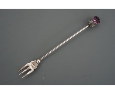 A George V silver pickle fork with thistle-form terminal, the latter set with an amethyst coloured stone, Die &amp; Lovekin L