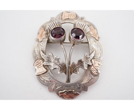 A Scottish silver brooch, modelled as a pair of thistles within a wreath of the same, faced with yellow metal and set with am