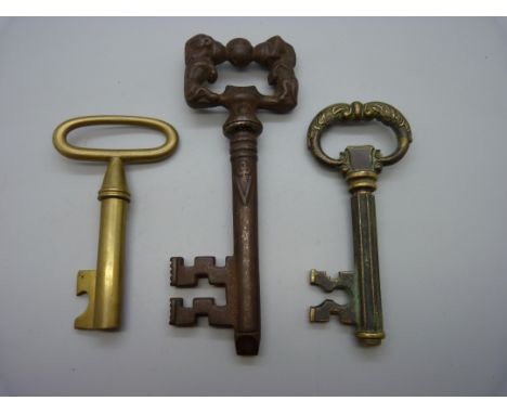A large cast iron key shaped corkscrew and two brass corkscrews 