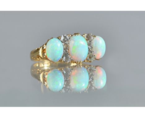 A gold, opal and diamond ring, mounted with three oval opals and with two rows of four small cushion shaped diamonds mounted 