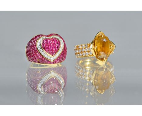 A ruby and diamond set dress ring of bombe heart design, set with calibre cut rubies collet set in a heart shape, enclosed by