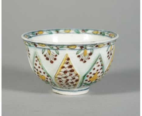 A Kutahya type teabowl, 18th century or later, the sides moulded with lappets painted with flowers alternating with a scale p