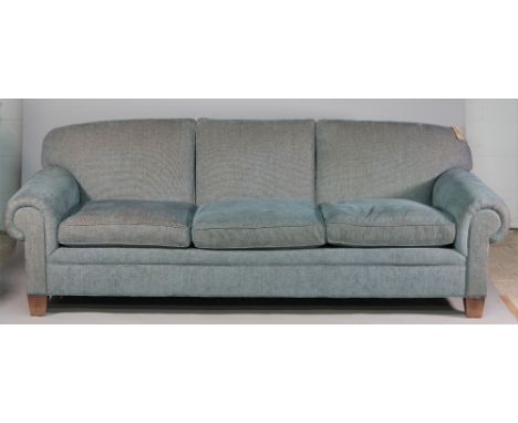 A large modern blue upholstered sofa with roll over arms on tapering block supports, 243cm wide x 87cm high. 